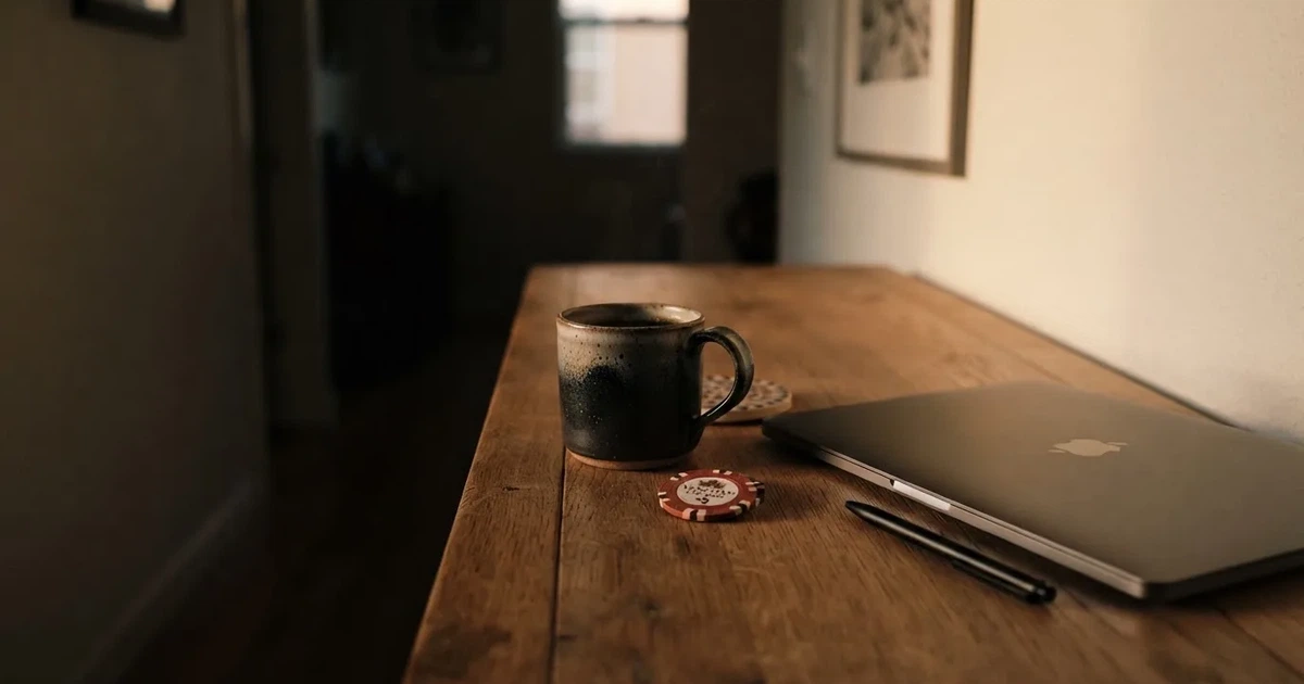 Kaffekopp och penna på ett smalt hallbord i skymning, en stängd bärbar dator vid sidan — 200 kr casino i sverige